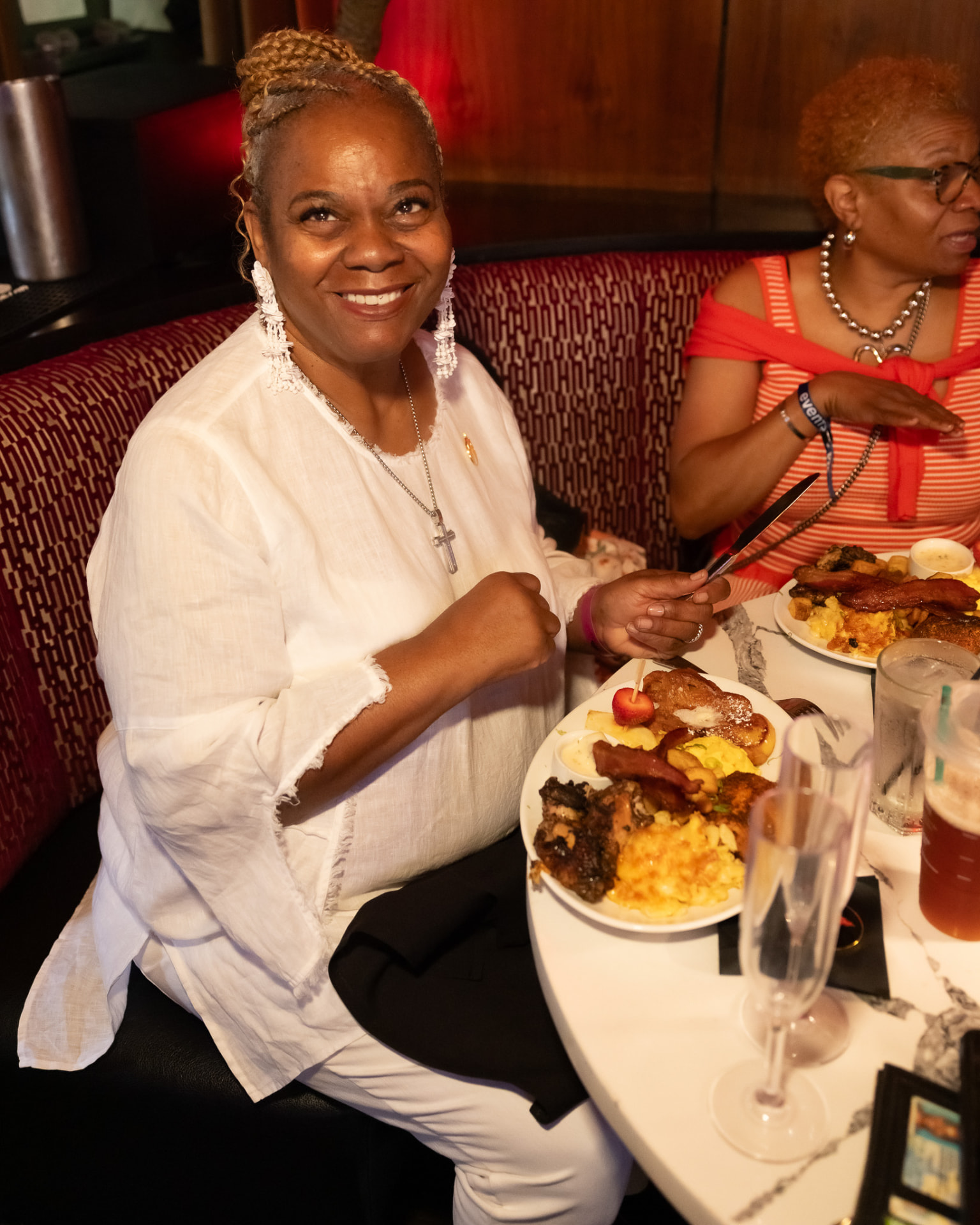Guests enjoying brunch plates and mimosas in a booth at the Fundraising Brunch
