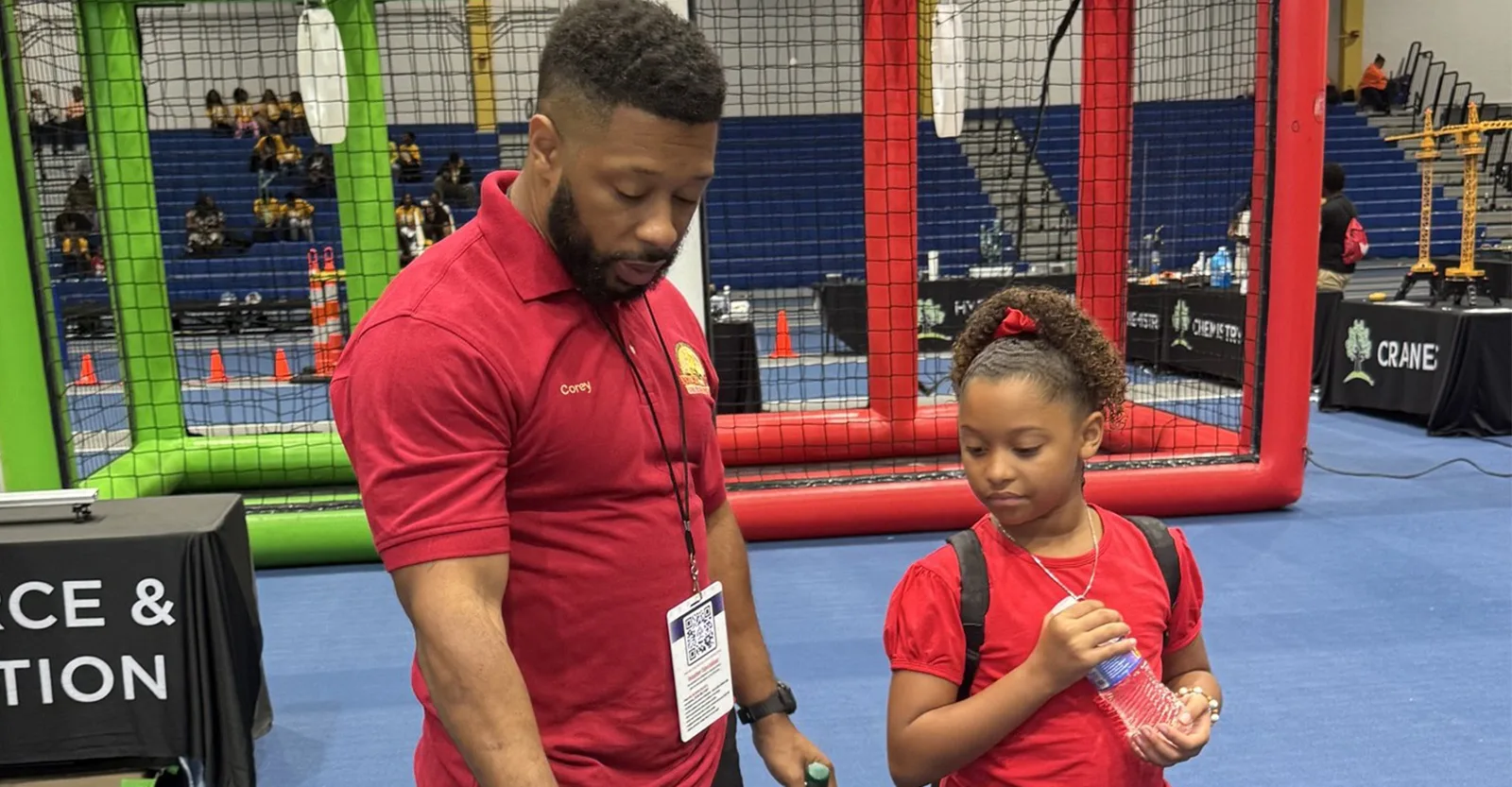 Krewe volunteer guiding a young girl through a hands-on STEM activity