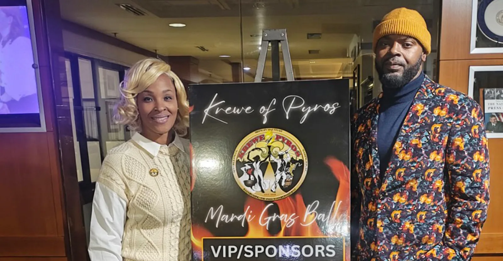 Members beside the Krewe of Pyros Mardi Gras Ball VIP and sponsors sign