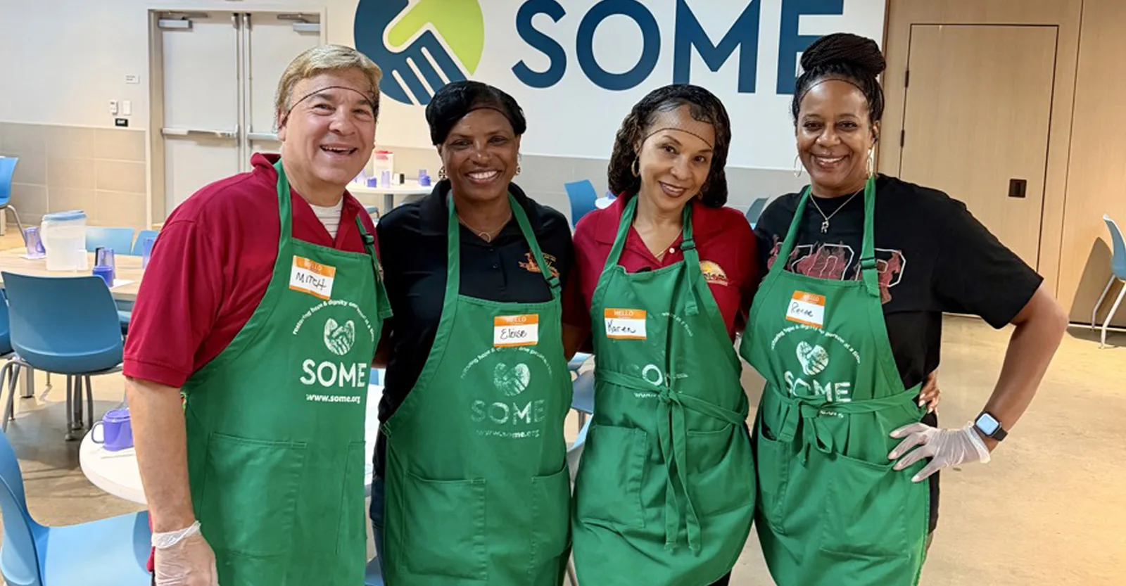 Krewe members volunteering in green aprons at a SOME community meal service