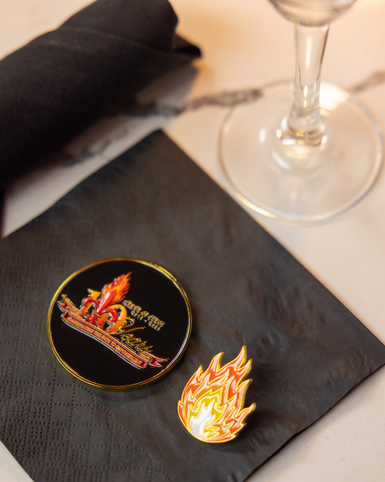 Krewe of Pyros 10 Years commemorative coin and flame lapel pin on a napkin