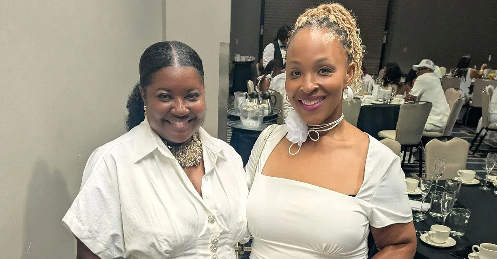 Two Krewe members in white at a gala reception in a hotel ballroom